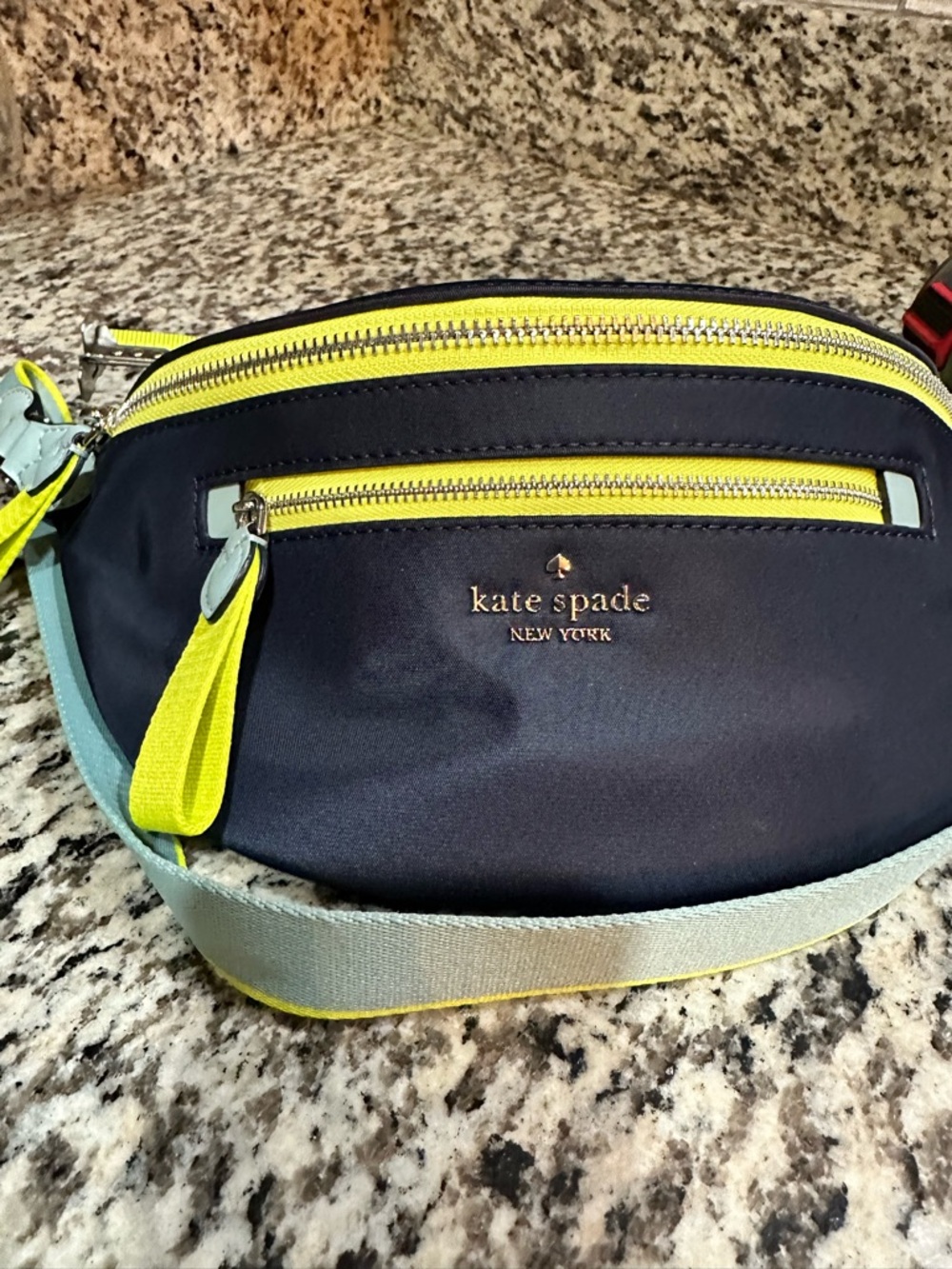 kate spade navy crossbody with neon yellow trim and light blue strap